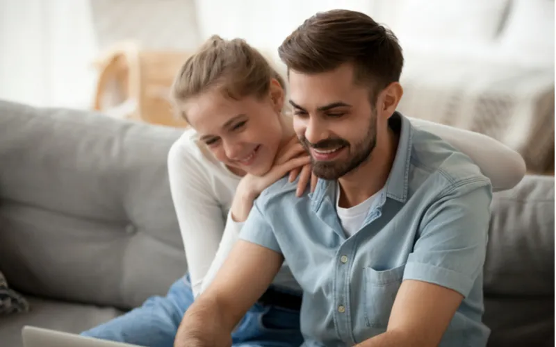 夫婦が家のソファに座って笑顔でパソコンを見ている