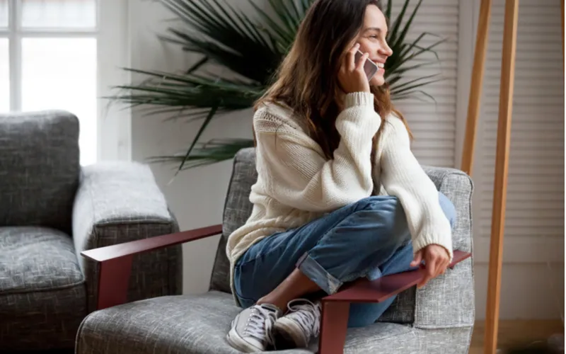 自宅で笑顔で旦那さんと電話している女性の写真