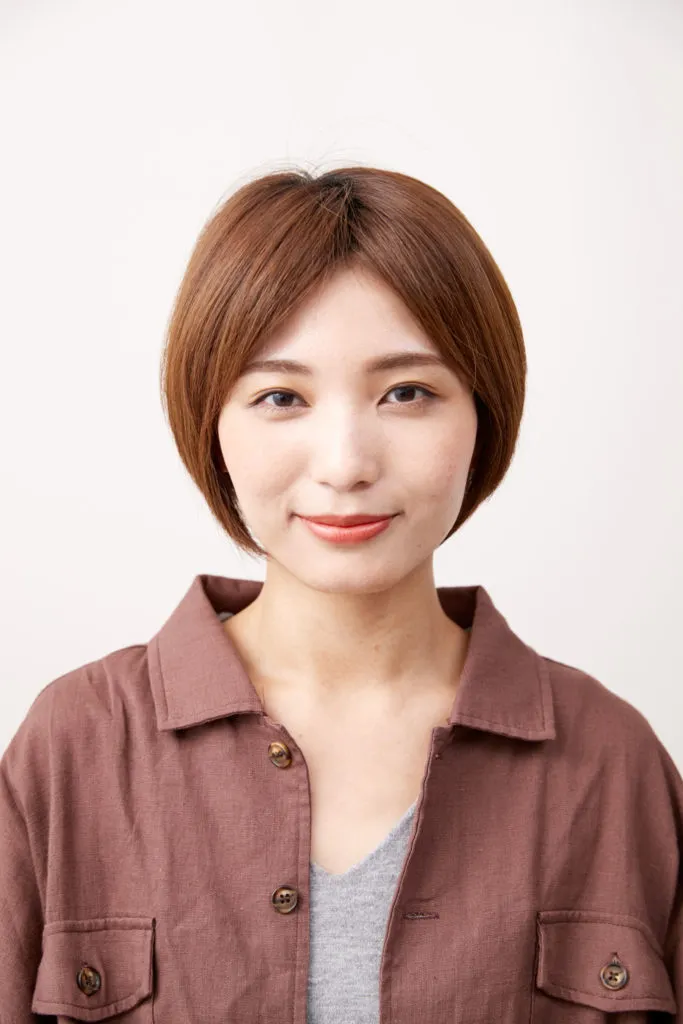 ショートから髪の毛を伸ばしている人の綺麗なショートカットの女性。髪色は王道ブラウンカラー