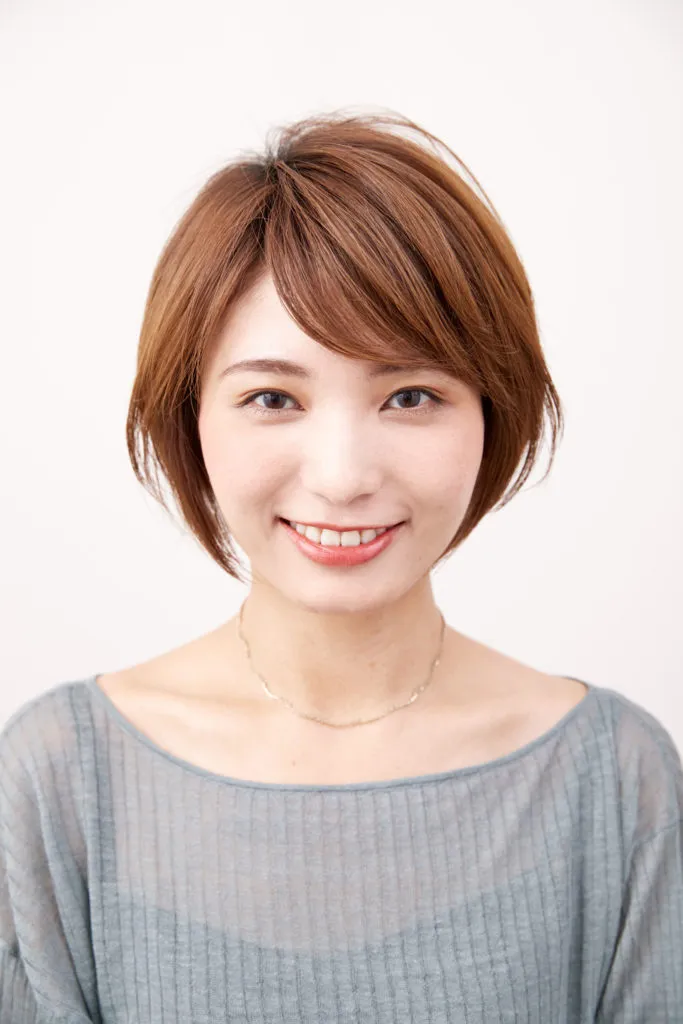 ショートヘアから伸ばしかけの女性が、前髪だけきれいにカットして整えた写真