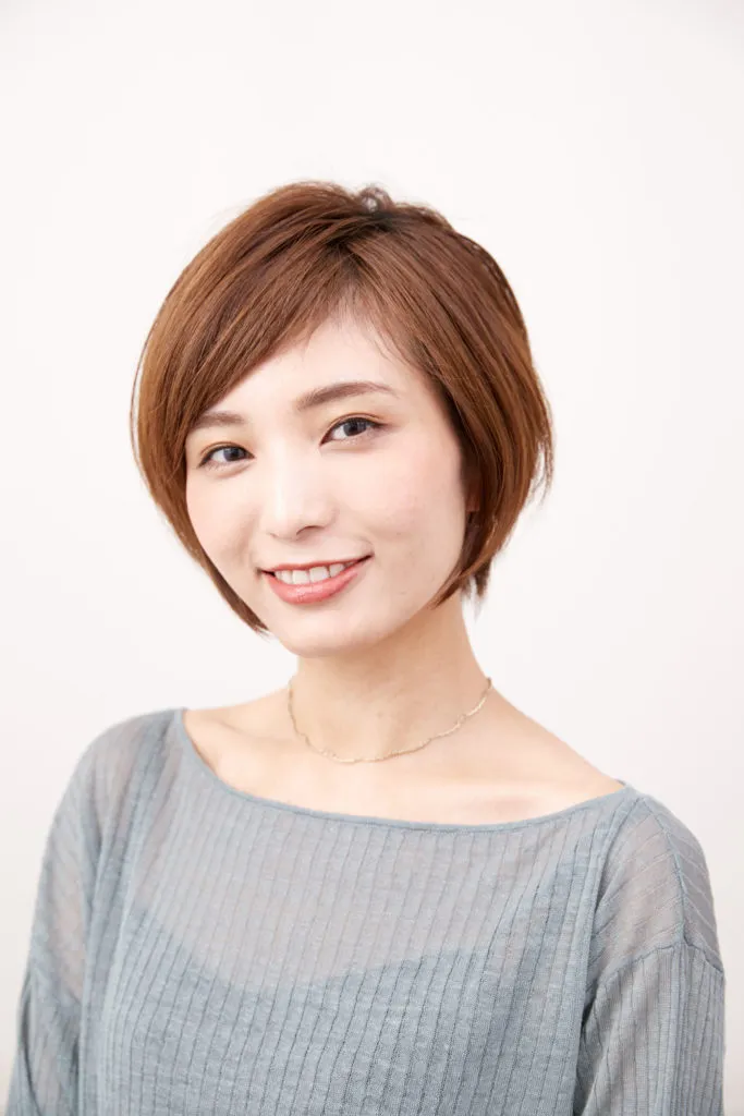 ショートヘアから伸ばしかけの女性が、髪の乾かし方を変えて分け目を変えて、フォルムも変えたヘアアレンジをしている