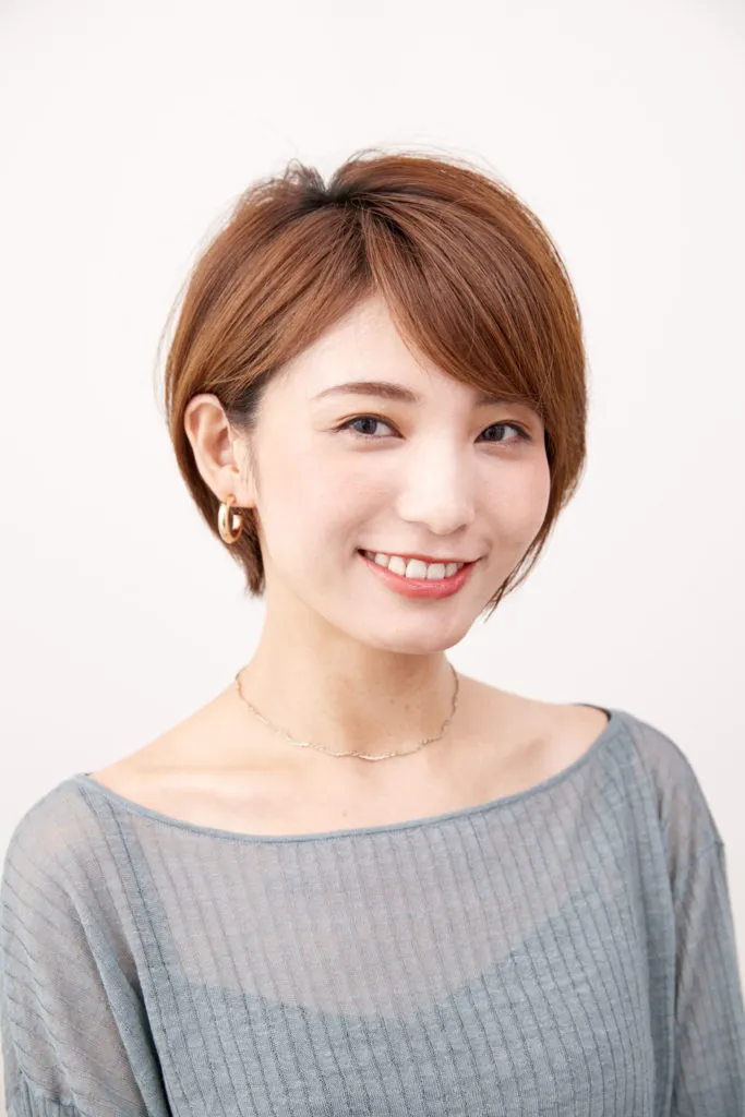 ショートヘアから伸ばしかけの女性が片耳だけかけてみてヘアアレンジをしている