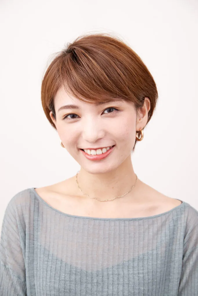ショートヘアから伸ばしかけの女性が両耳の髪の毛をかけてヘアアレンジをしている