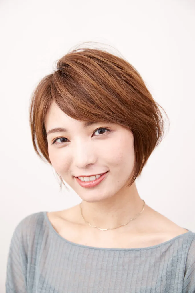ショートヘアから伸ばしかけの女性がワックスやスプレーでふんわりした質感のヘアアレンジをしている