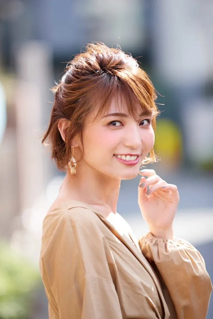 ショートヘアから伸ばしかけの女性が、ハーフアップのヘアアレンジをしている。ピンやゴムを使うアレンジ