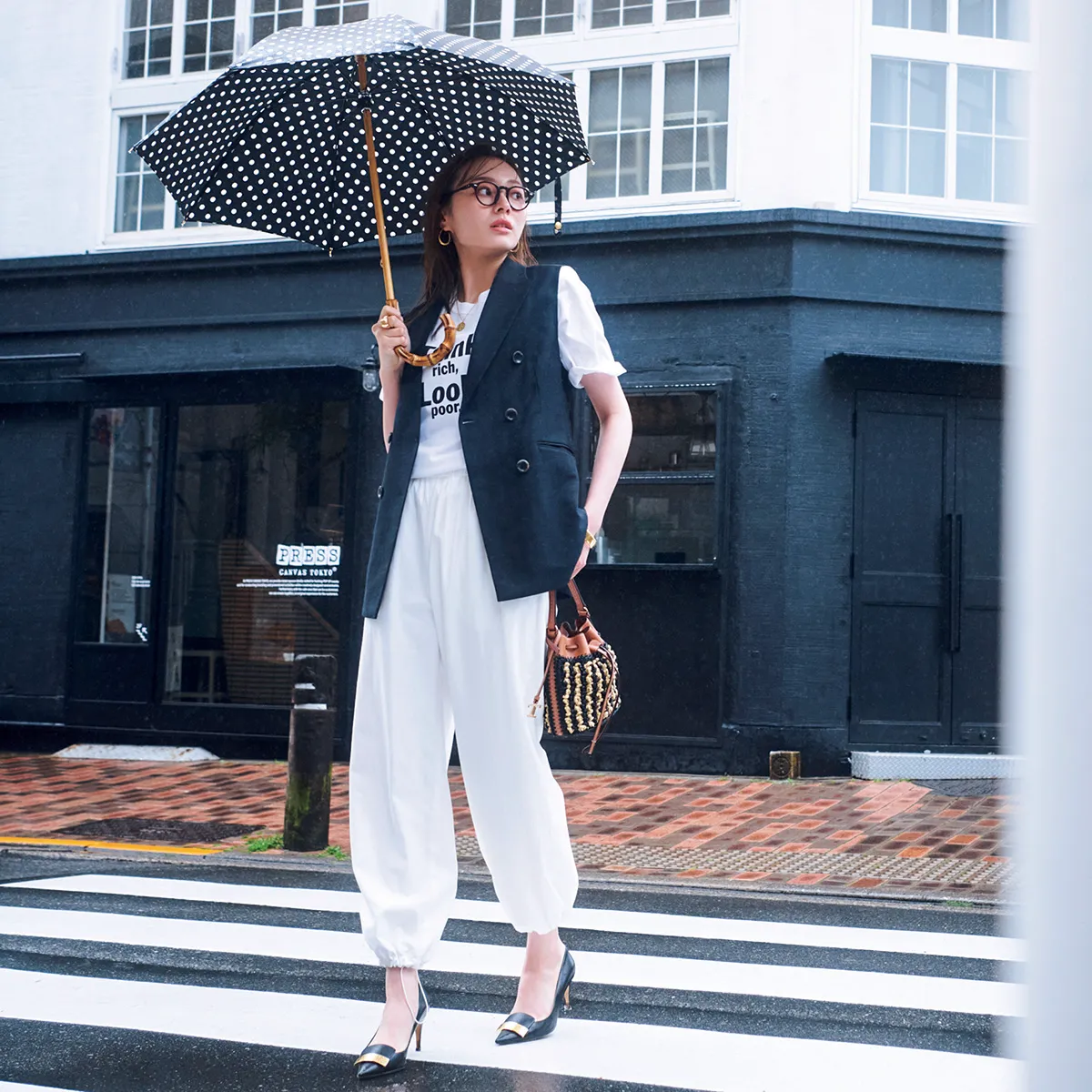 白ロゴT、白パンツに黒のジレを羽織ったオフィスカジュアルコーデ