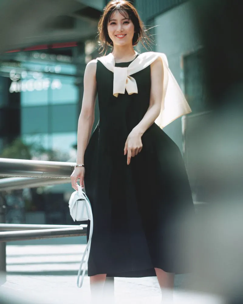 黒のノースリーブフレアワンピースに白カーディガンを肩に巻いたコーディネート