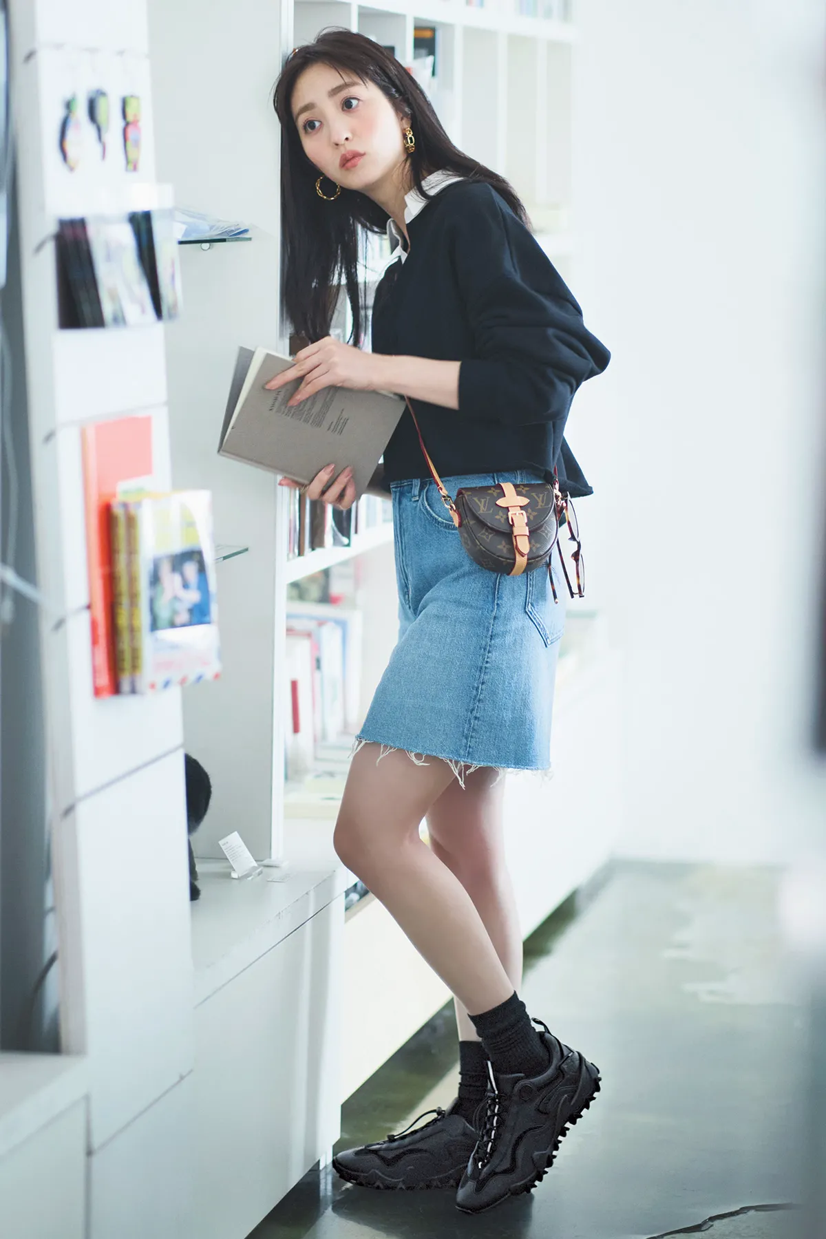 プルオーバー、ミニスカート、スニーカーを纏った堀田茜さん。耳には大ぶりピアスをつけている。
