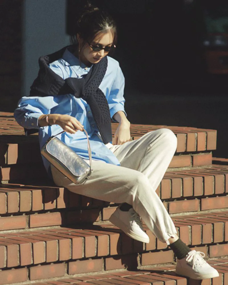 ブルーシャツにスウェットパンツ、白スニーカーの女性