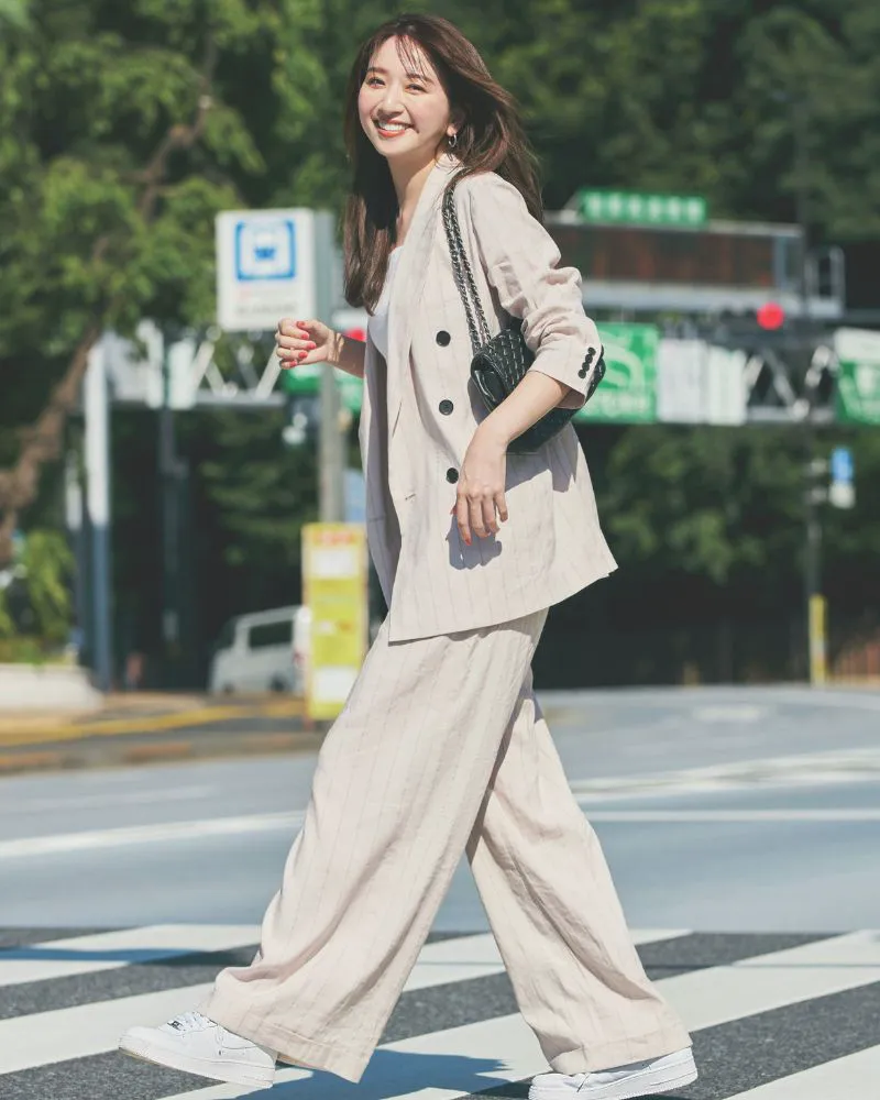 ジャケット、パンツのセットアップに白スニーカーを履いた女性