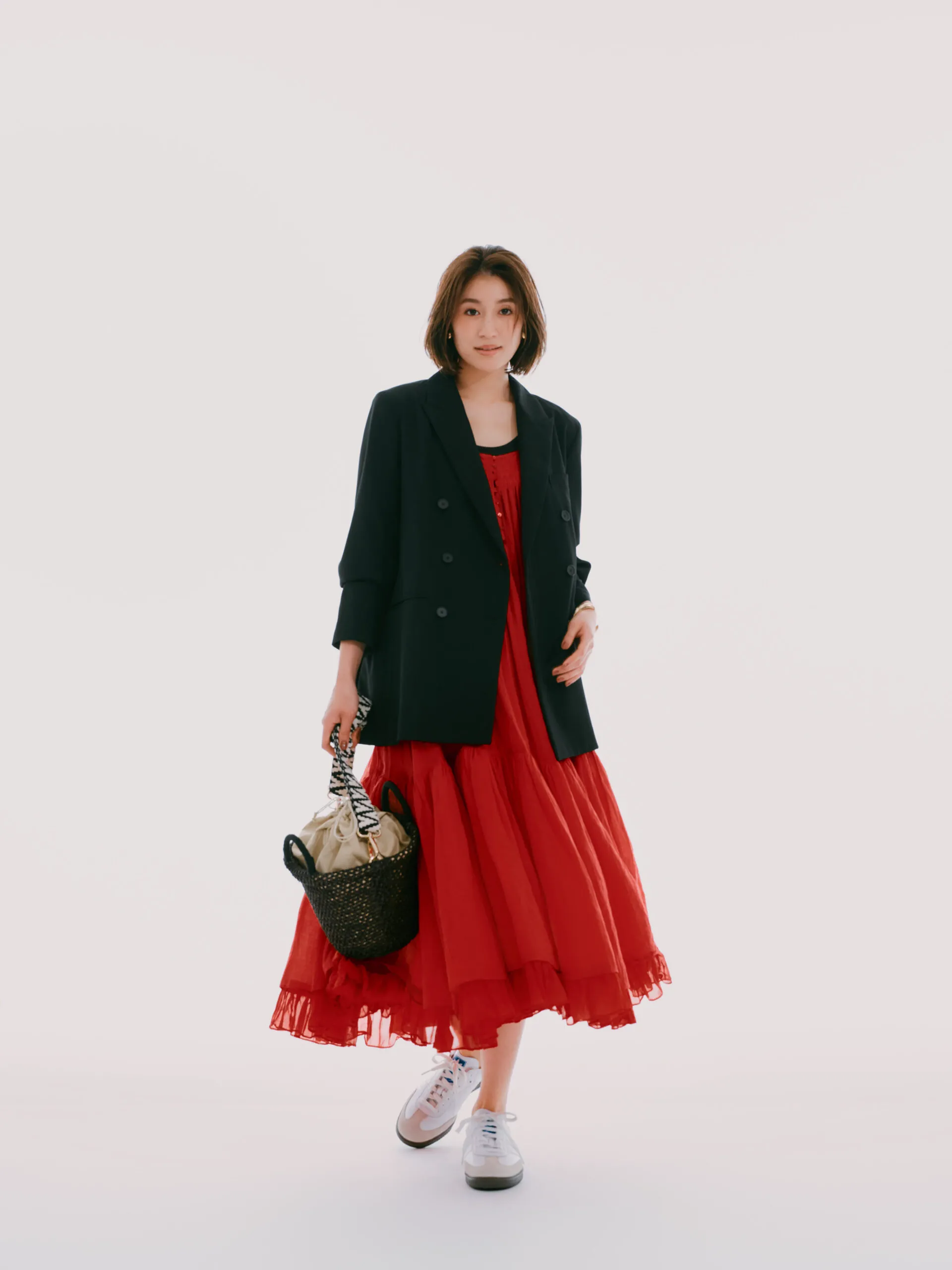 赤いワンピースにジャケット、白スニーカーを合わせた女性
