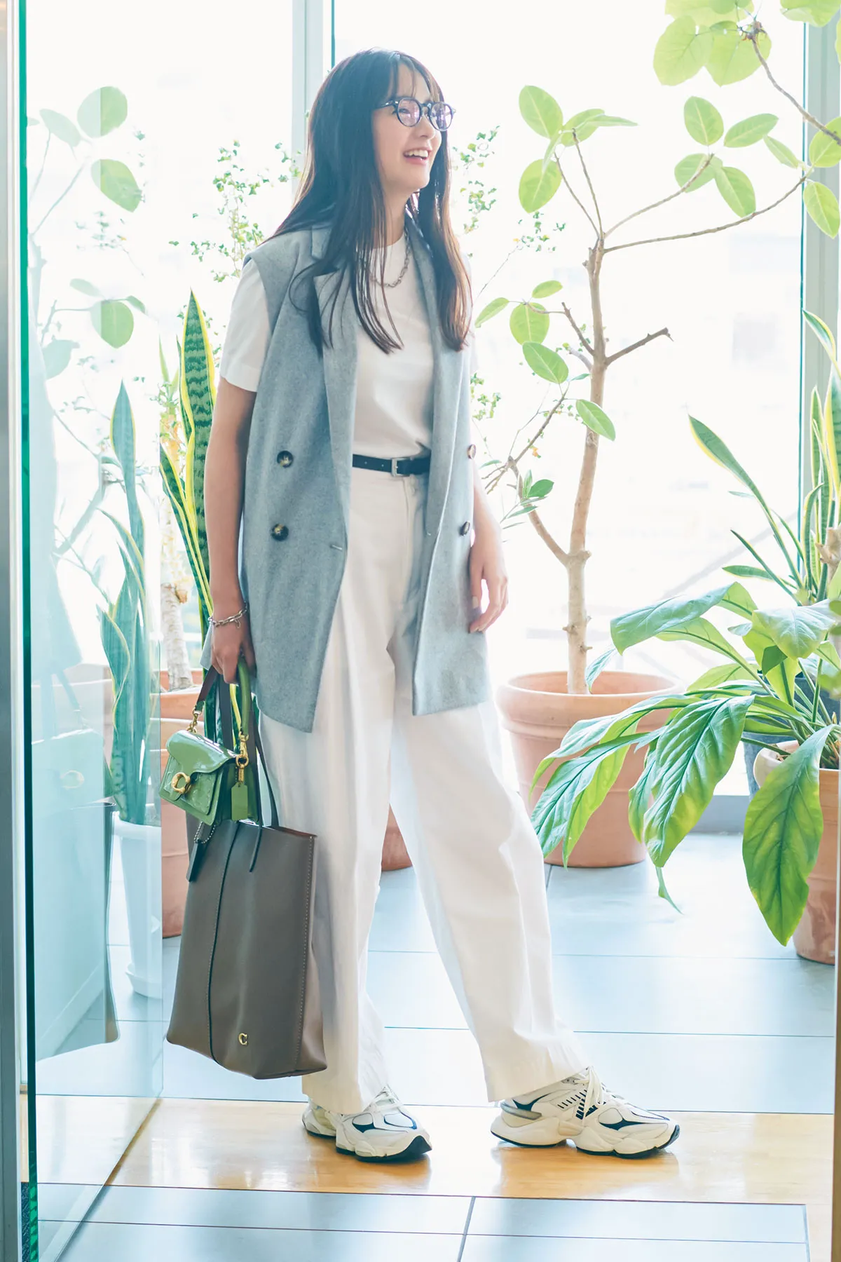 白Tシャツ、パンツにジレ、白スニーカーを合わせた女性