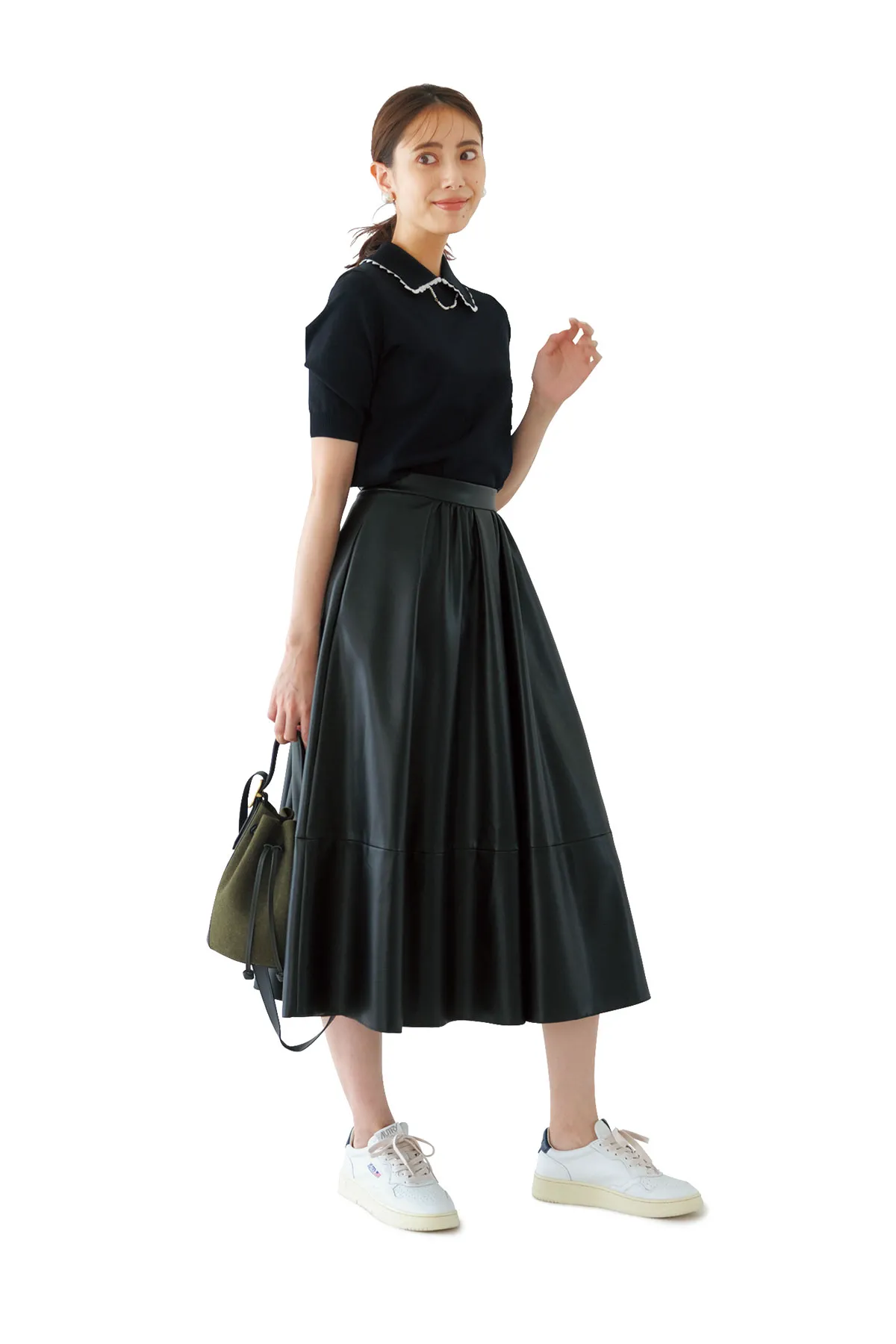 黒の半袖ニットにフレアスカート、白スニーカーを履いた女性