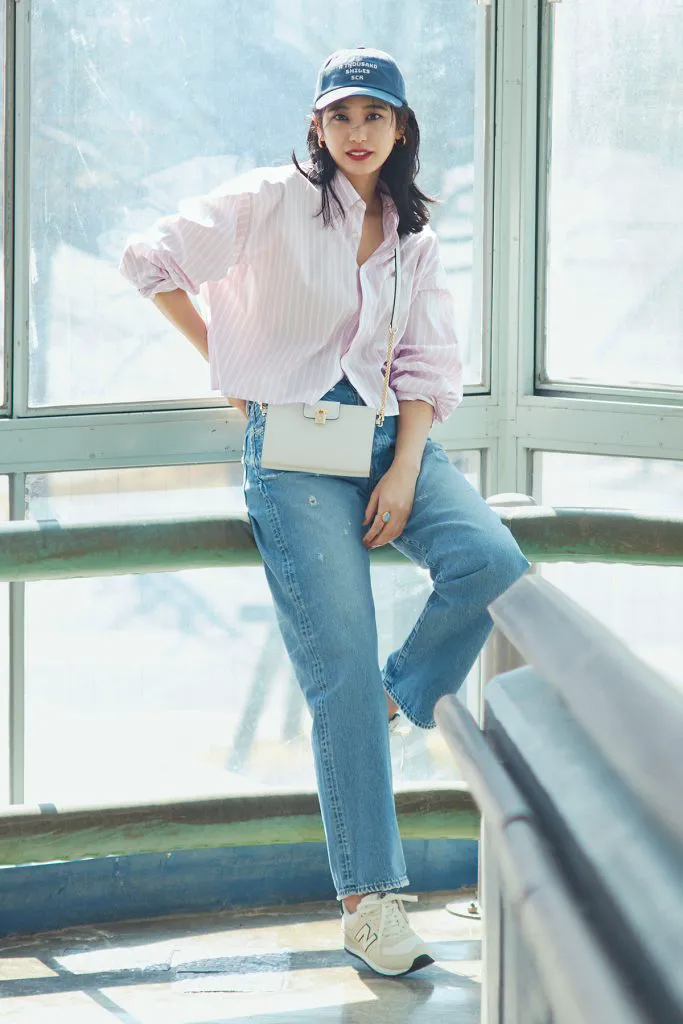 ピンクのシャツにデニム、白スニーカーを合わせた女性