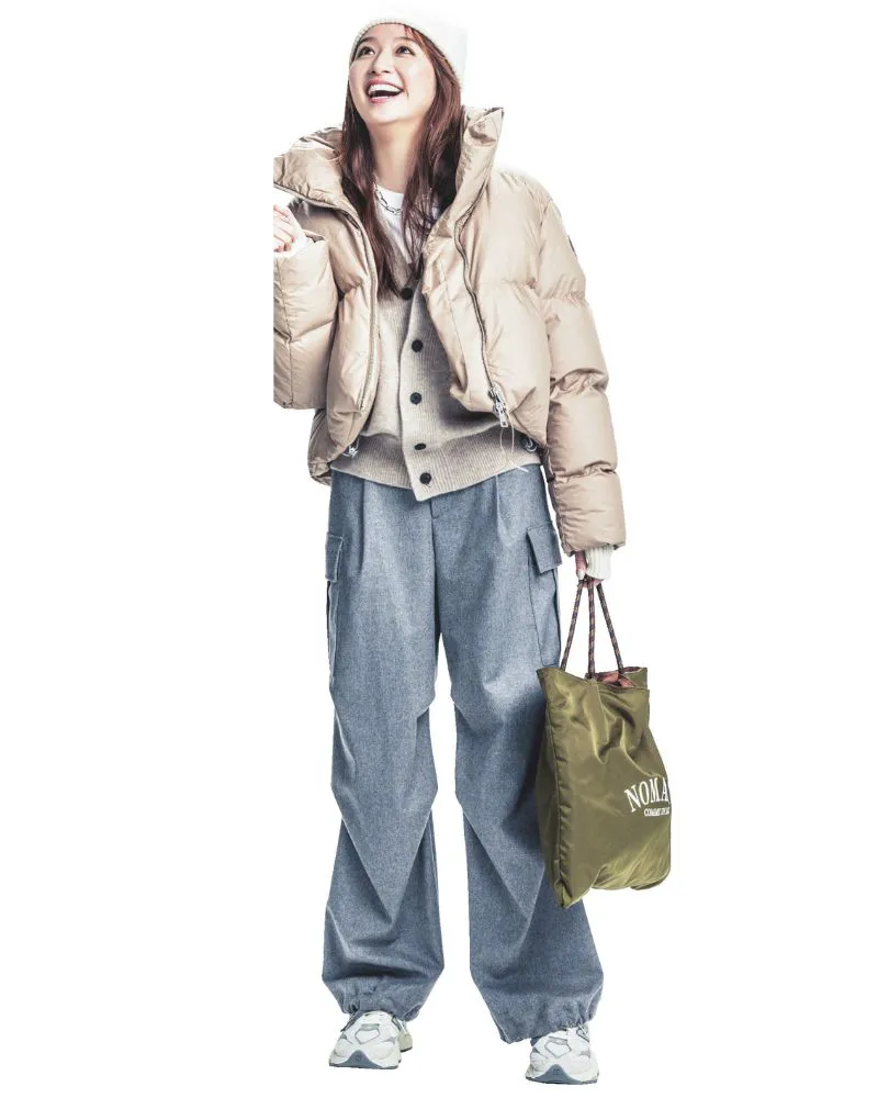 ベージュのダウンジャケットにグレーのカーゴパンツ、白スニーカーを履いた女性