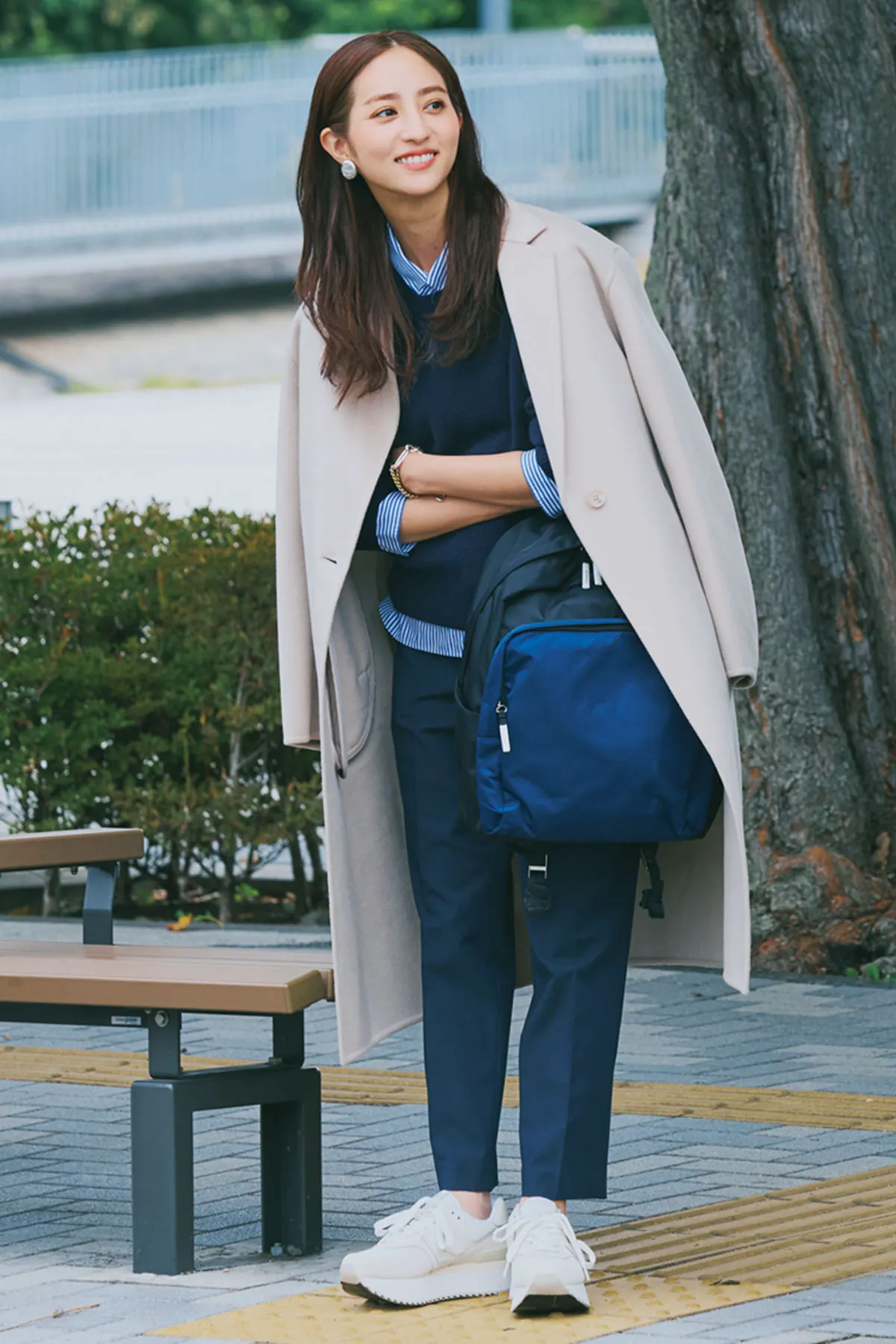 ネイビーのスリムパンツにニット、白スニーカーを履いた女性