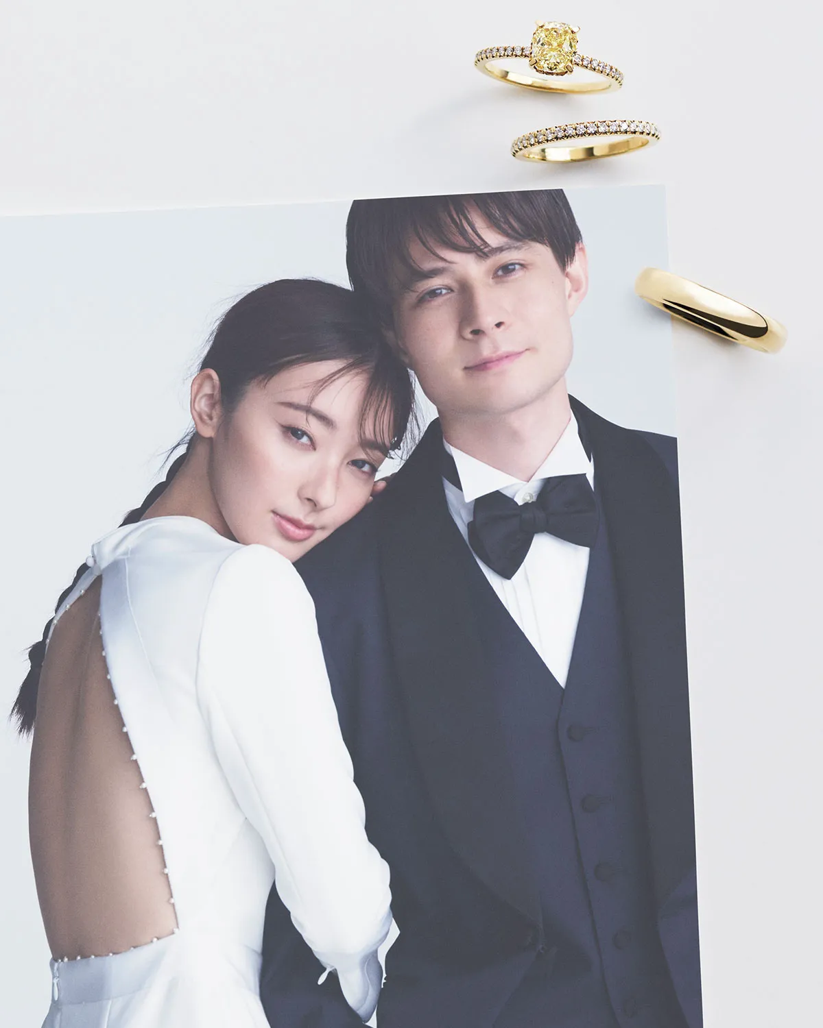ウエディング姿の宮本茉由さんと、タキシード姿のシールズ啓司さんが並んでいる姿を捉えた写真の右上に、ティファニーのリング「ティファニートゥルー」、エタニティリング「ティファニー ソレスト」、リング「ティファニー フォーエバー」が縦に並んでいる様子。