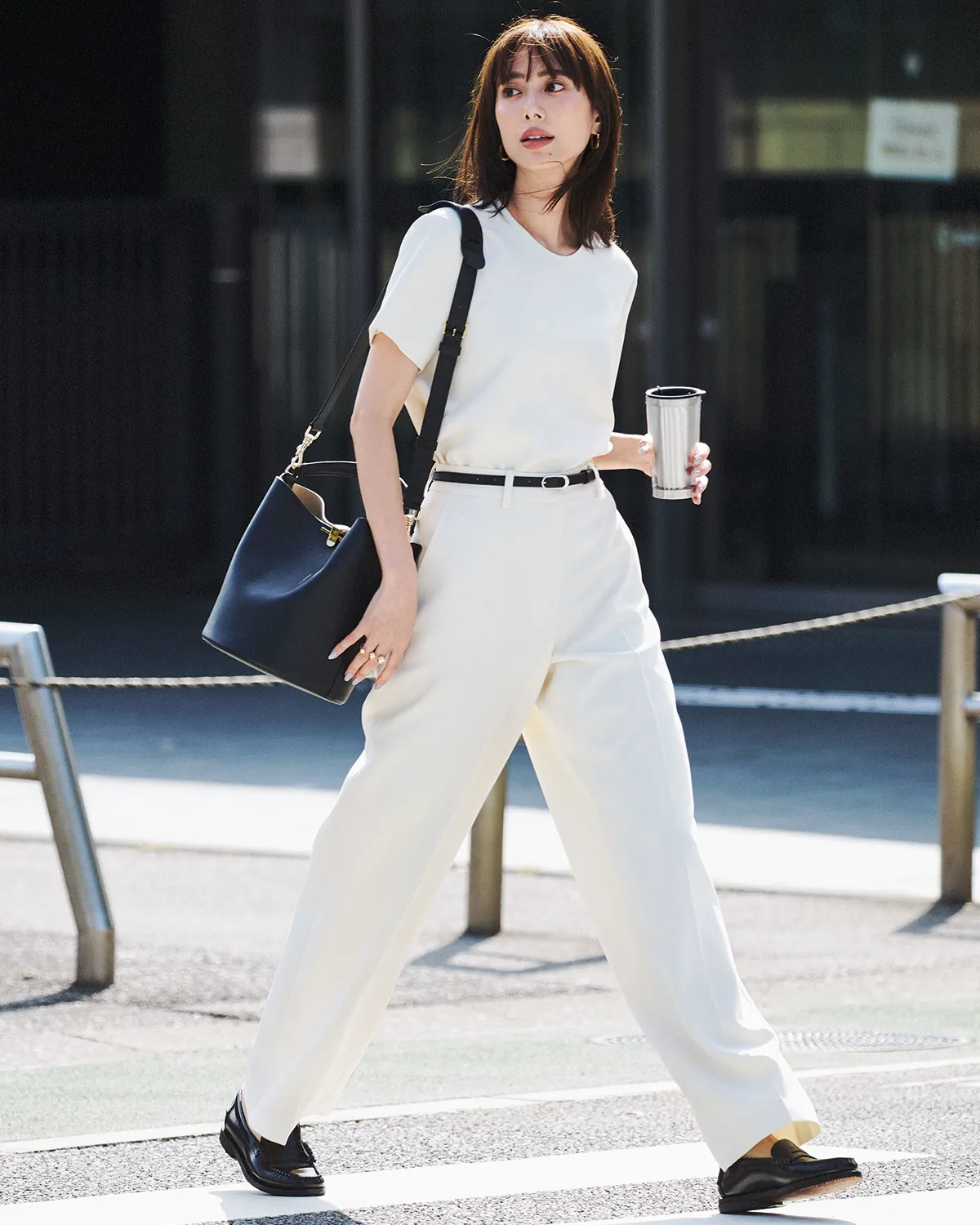 白Tシャツ、パンツ、ローファーを履いた女性