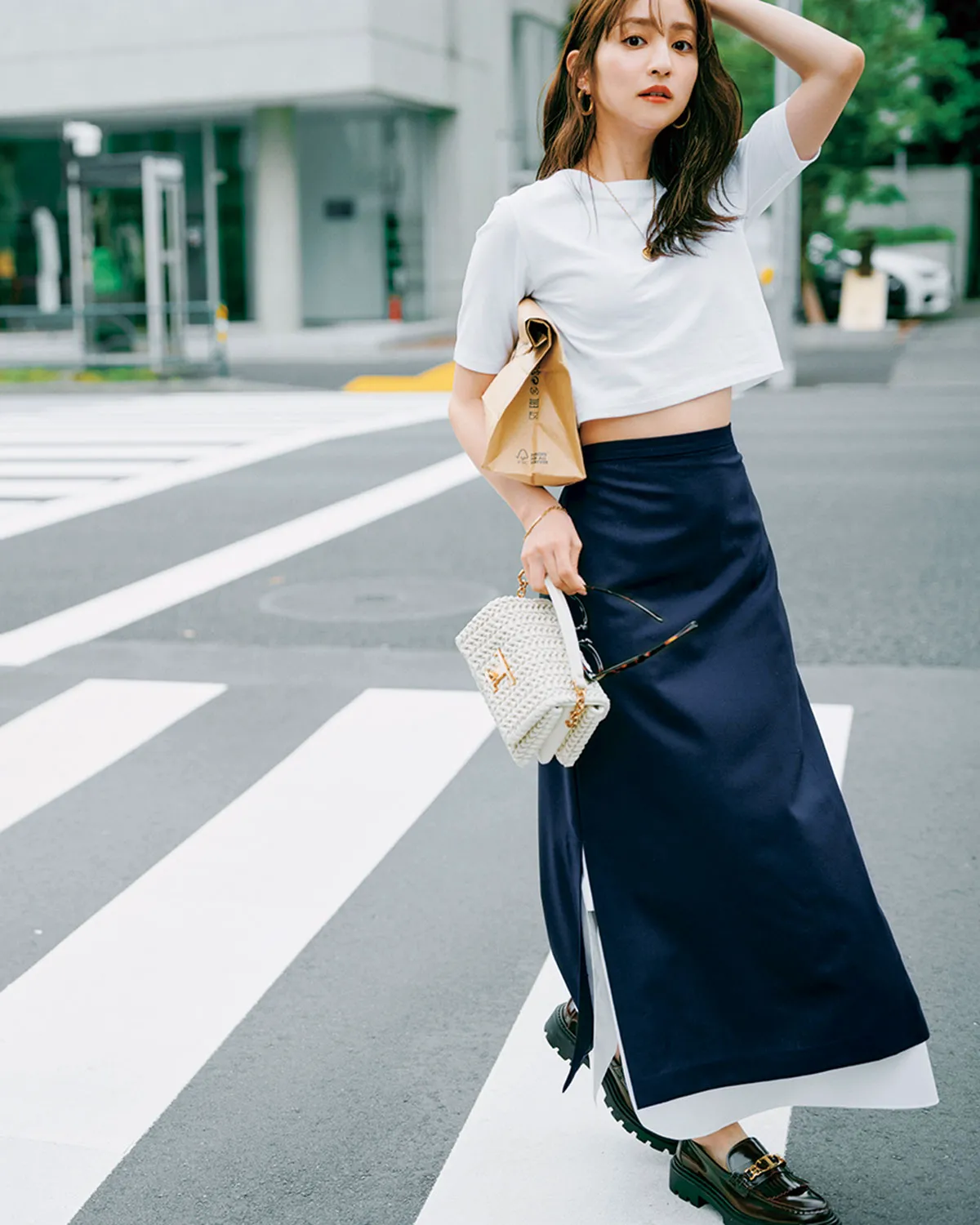 白Tシャツにネイビーのロングスカート、ローファーを履いた女性