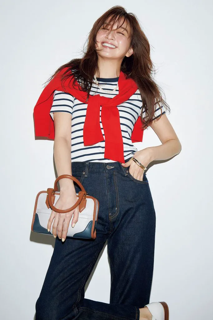 ボーダーTシャツ、デニム、赤のカーディガンを合わせた女性