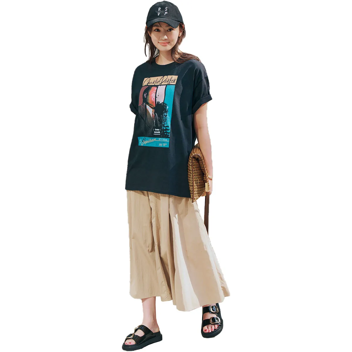 ロックTシャツ、ベージュのロングスカート、サンダル、キャップを合わせた女性