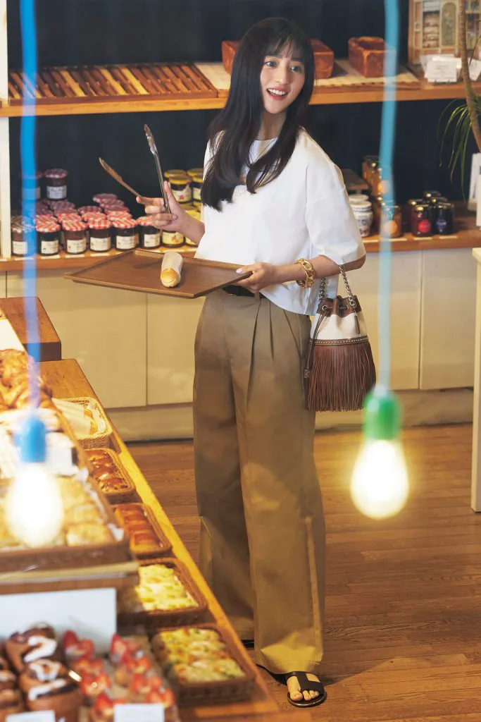 白Tシャツ、キャメルのパンツ、サンダルを履いた女性