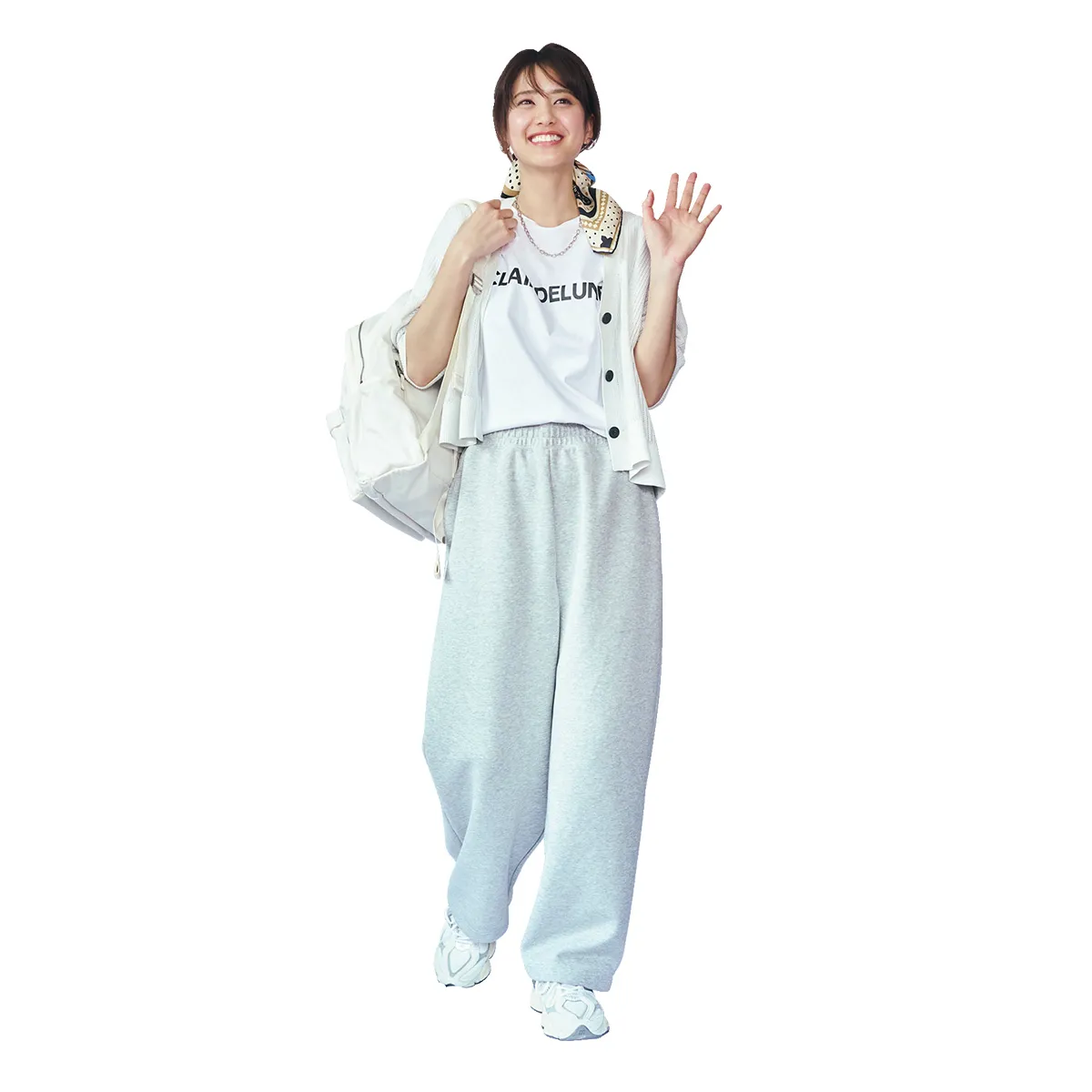 ロゴTシャツにカーディガン、スウェットパンツ、スニーカーを履いた女性