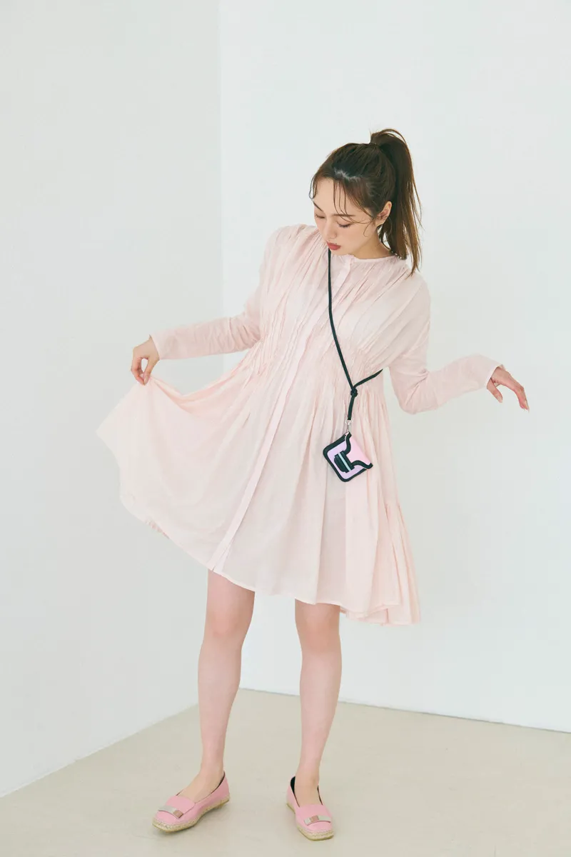 ピンクのシャツワンピース、エスパドリーユ、ミニバッグを合わせた女性