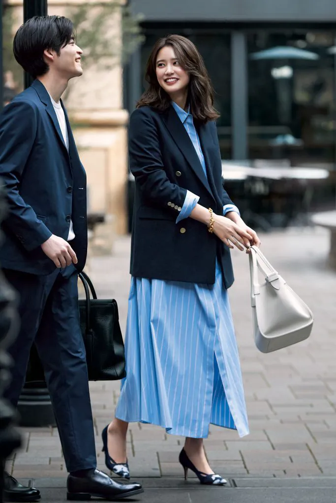 ブルーのストライプシャツワンピース、ジャケット、ヒールを合わせた女性