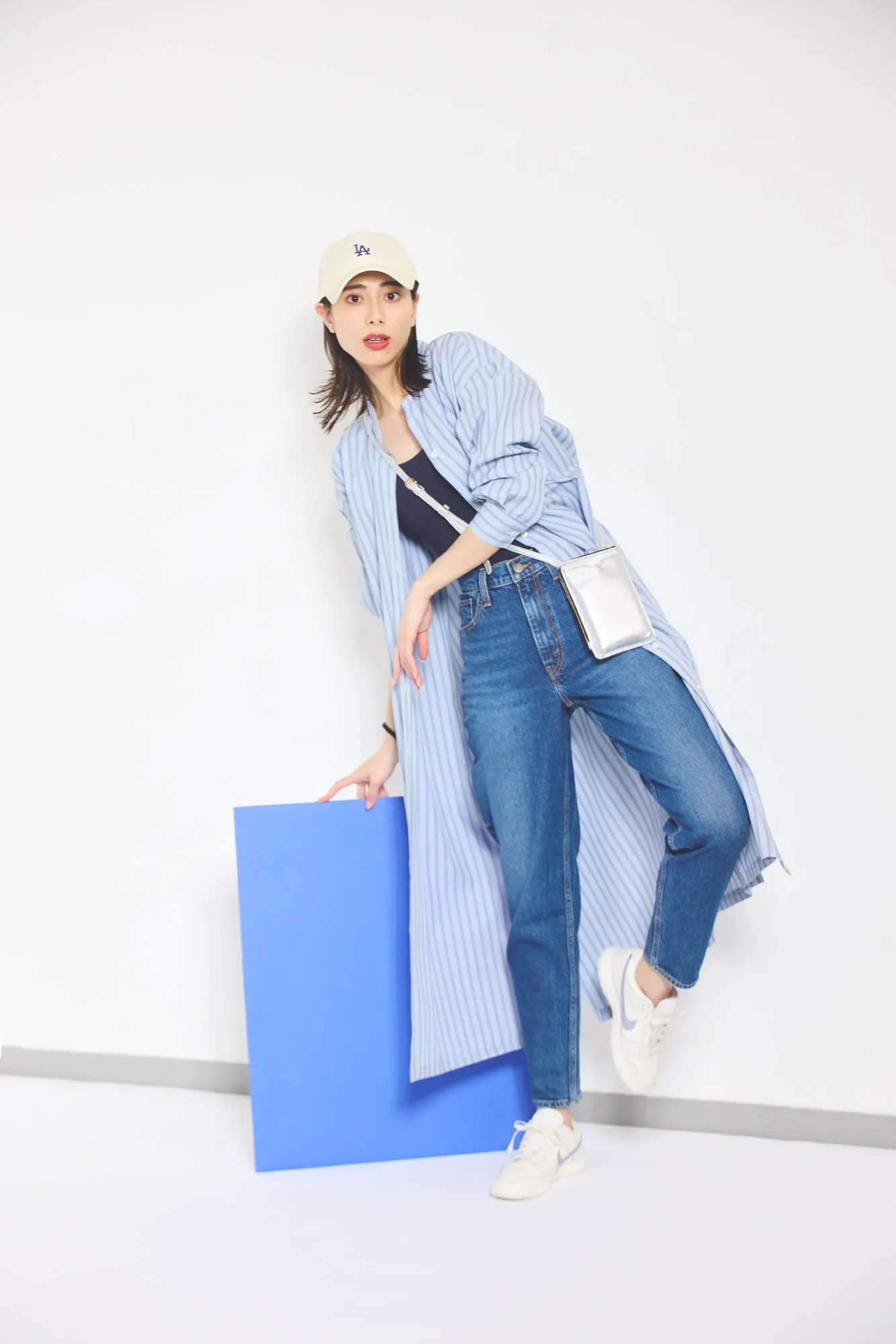 ストライプのシャツワンピース、黒トップス、デニムを履いた女性