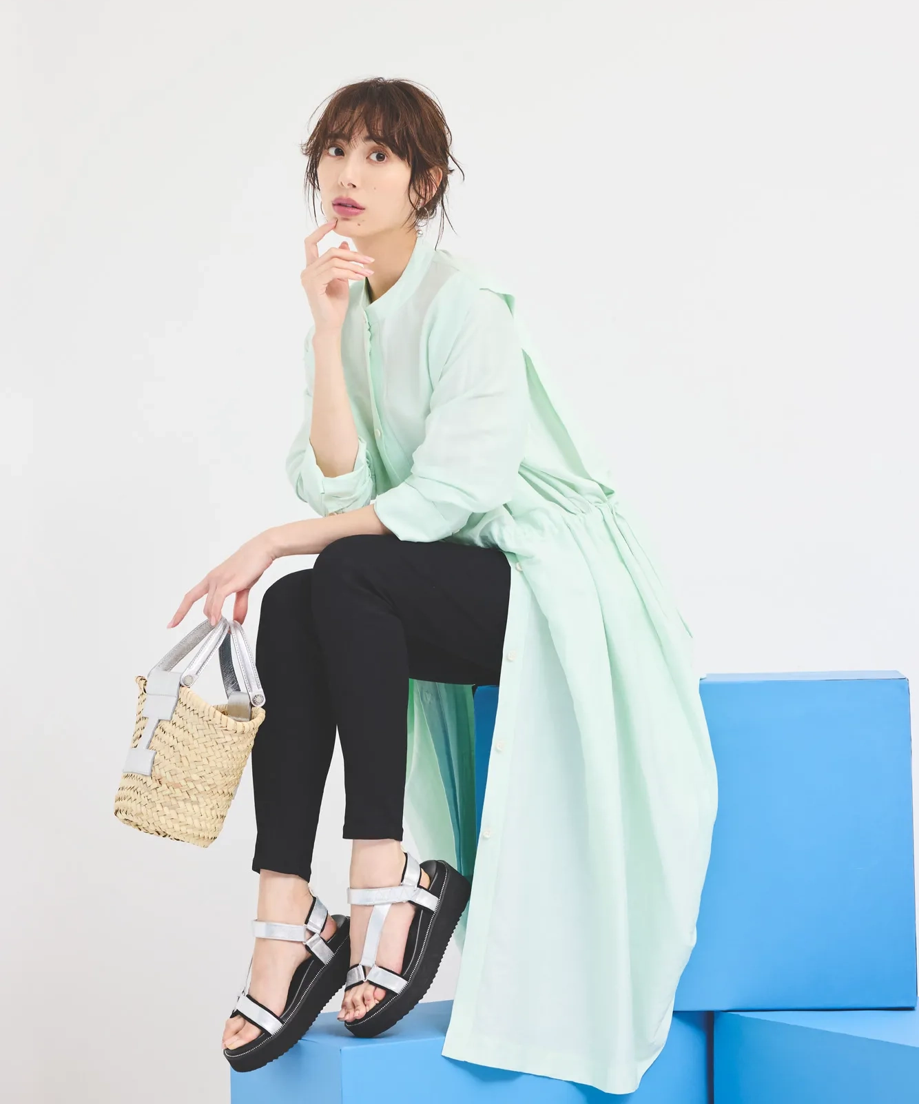 ミントグリーンのシャツワンピース、黒スキニー、フラットサンダルを履いた女性
