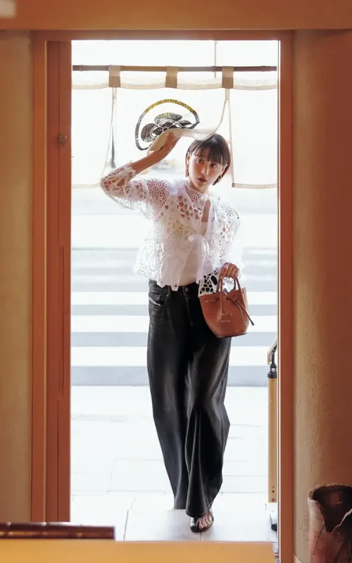 可愛げレースブラウスと黒デニムコーデで、茶色のバッグを持った女性