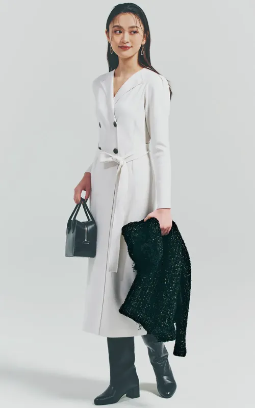 フォーマルな白ワンピースに、黒ロングブーツ、バッグ、アウターを身につけている女性