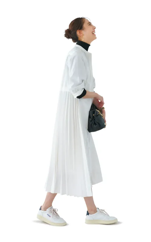 白ワンピース、黒タートルニット、白ネイビースニーカースタイルの女性