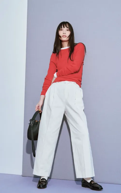 赤トップスと白チノパンツに、黒のシューズとバッグを身につけた女性