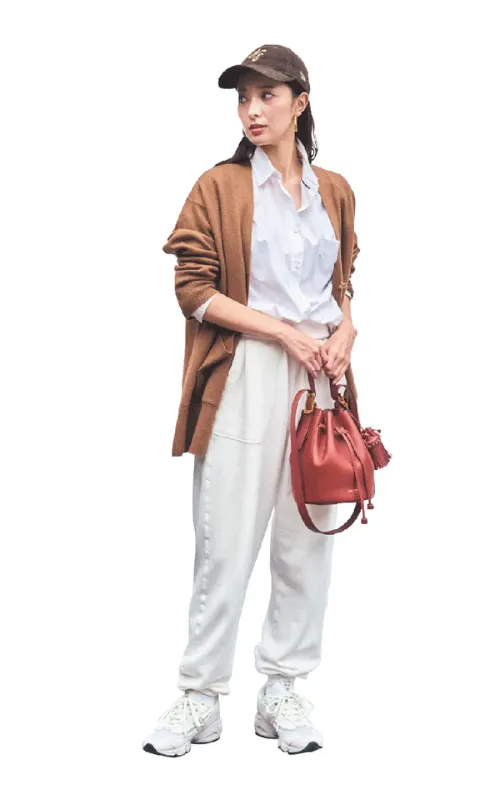 上下白コーデに、ブラウンキャップ、ブラウンカーディガンを身につけ、赤のバッグで差し色をプラスしている女性