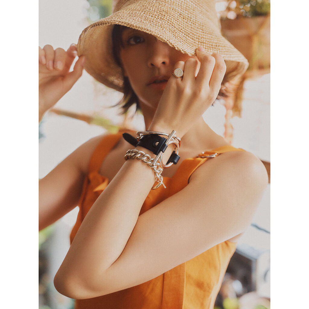 オレンジトップスにシルバージュエリーのコーデ