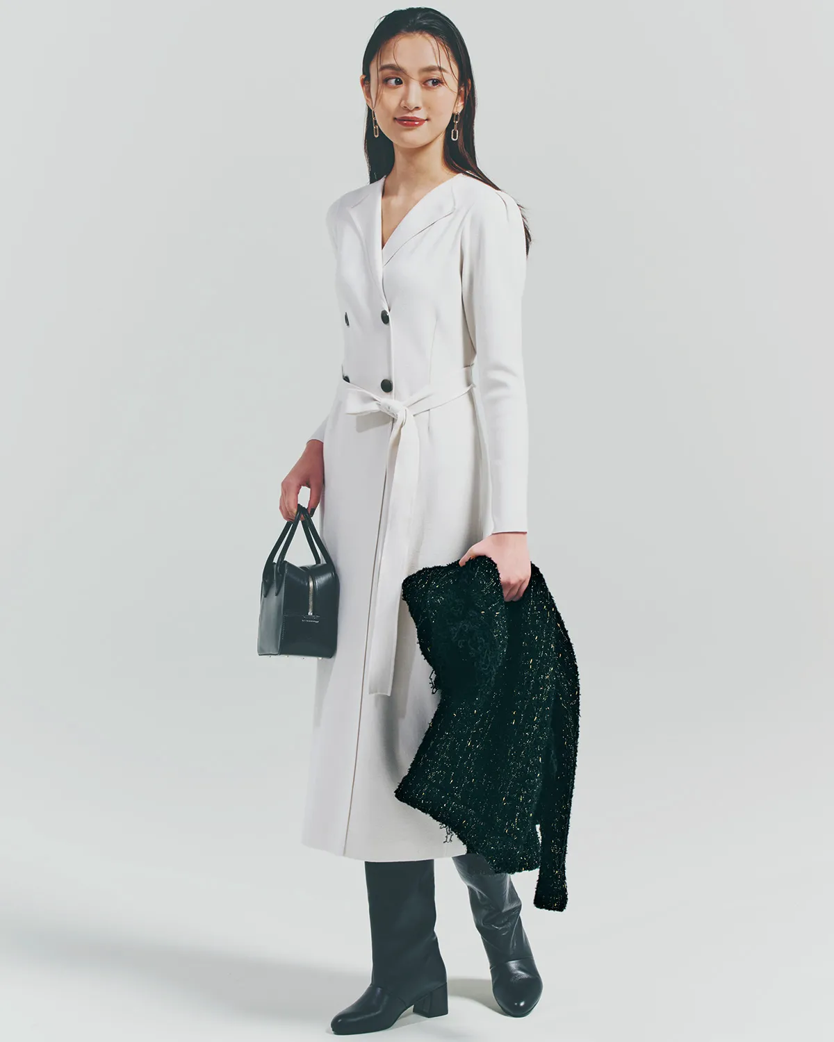 フォーマルな白ワンピースに、黒ロングブーツ、バッグ、アウターを身につけている女性