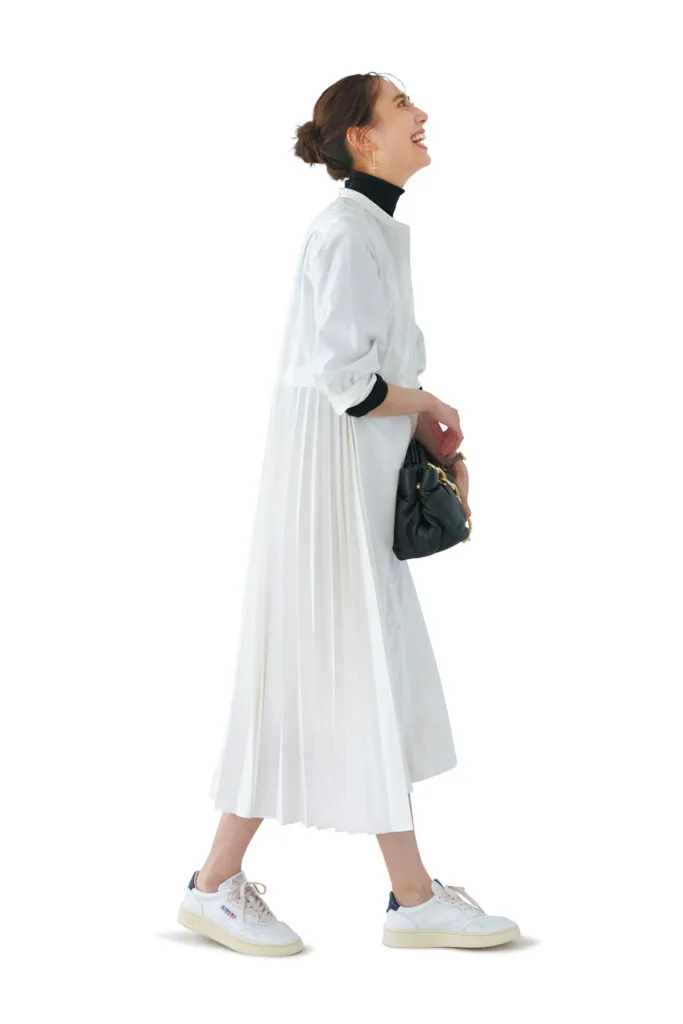 白ワンピース、黒タートルニット、白ネイビースニーカースタイルの女性