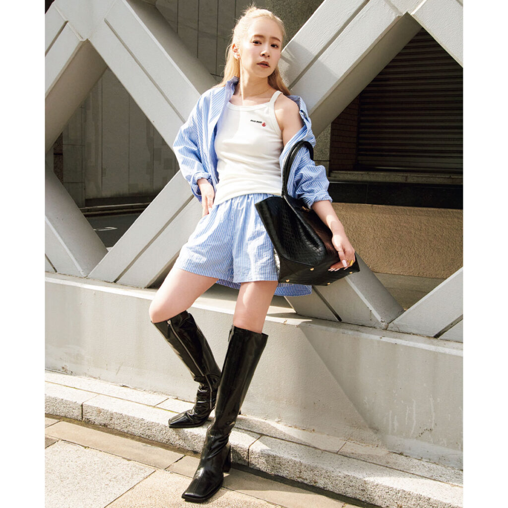 白キャミソールにブルーのストライプシャツとハーフパンツのセットアップにロングブーツのコーデ