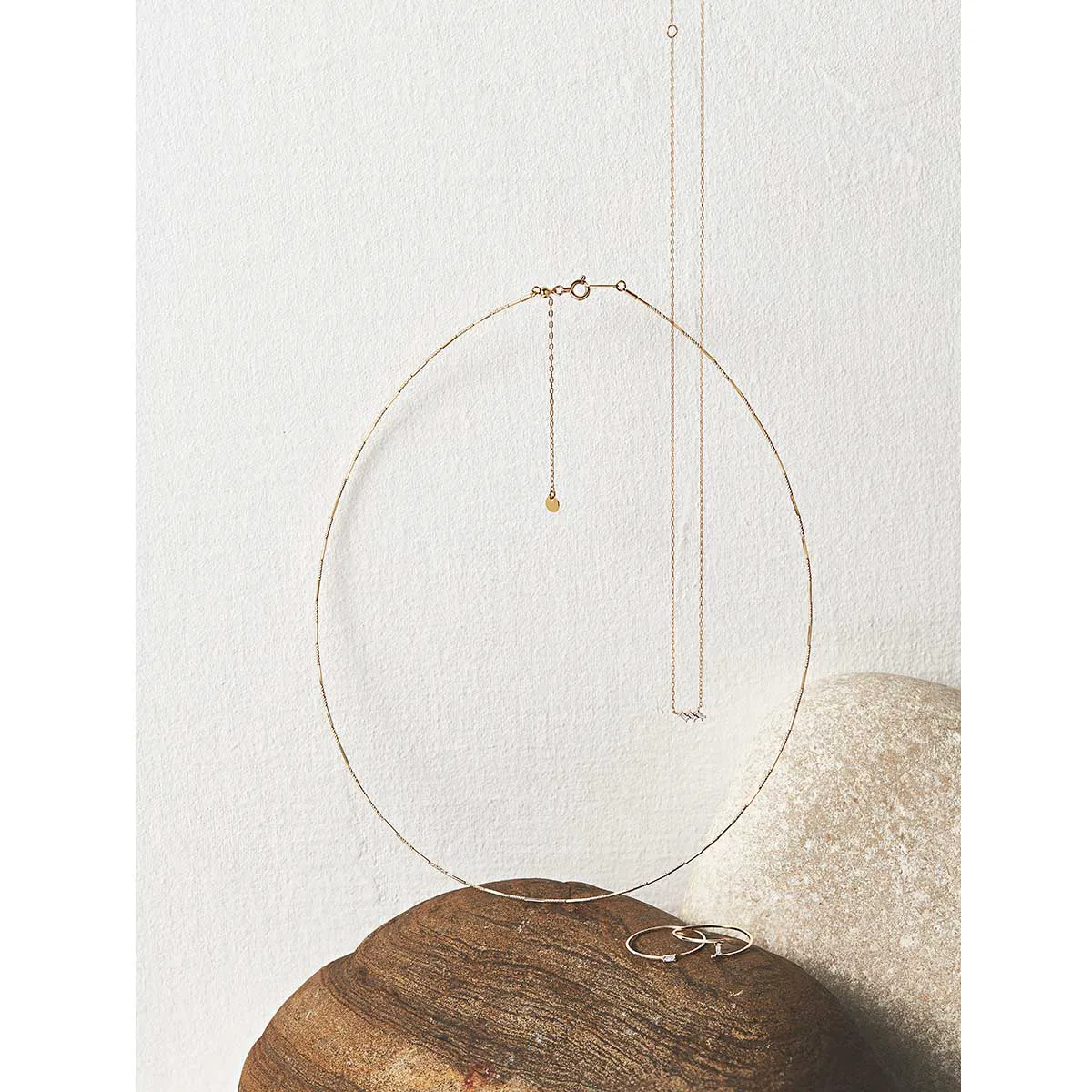 ヴイエー ヴァンドーム青山のネックレスが2つ並んでいる様子。近くの木の置物の上にはピアスが置いてある。