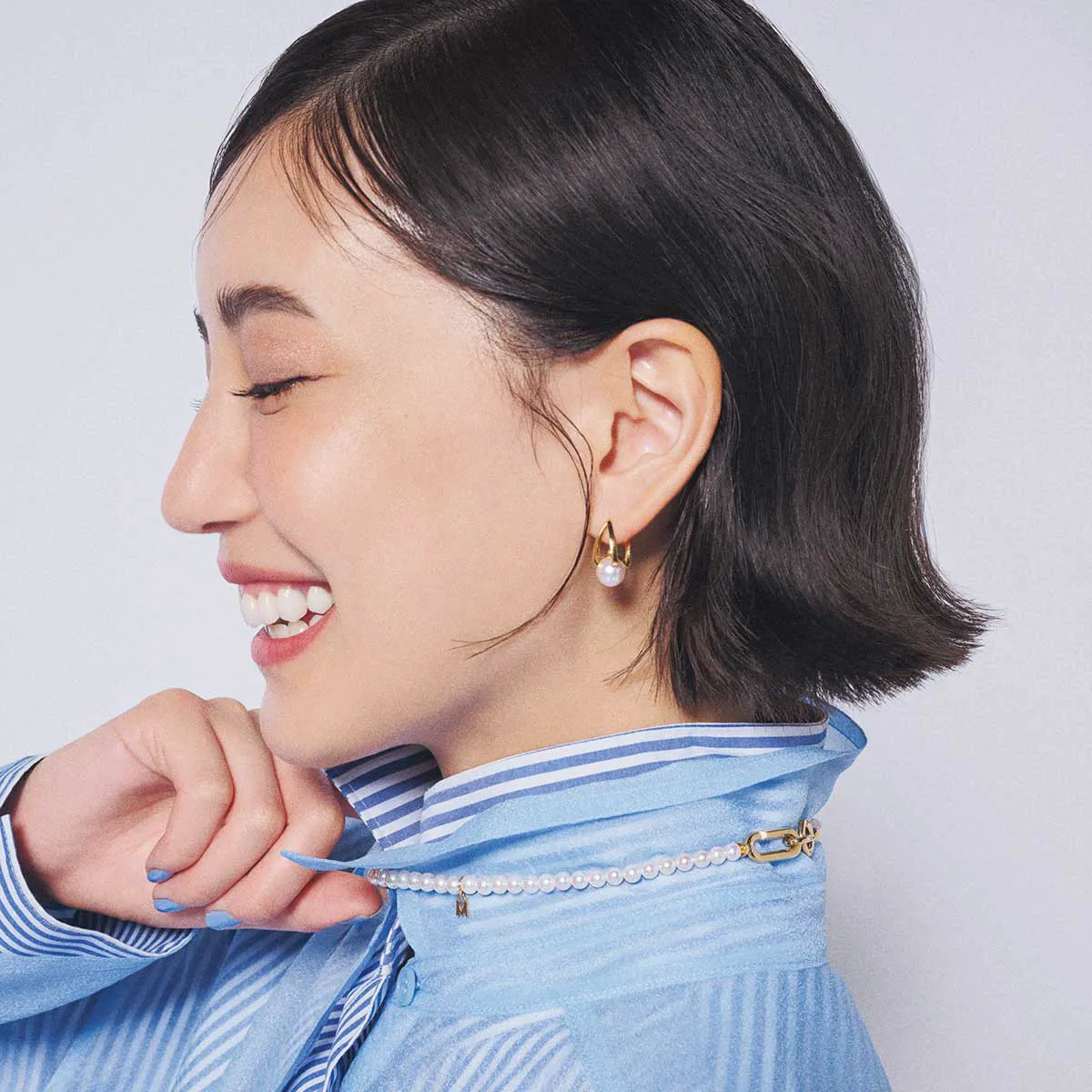 ミキモトのパールネックレスをつけている、ストライプシャツ姿の藤井夏恋さん。