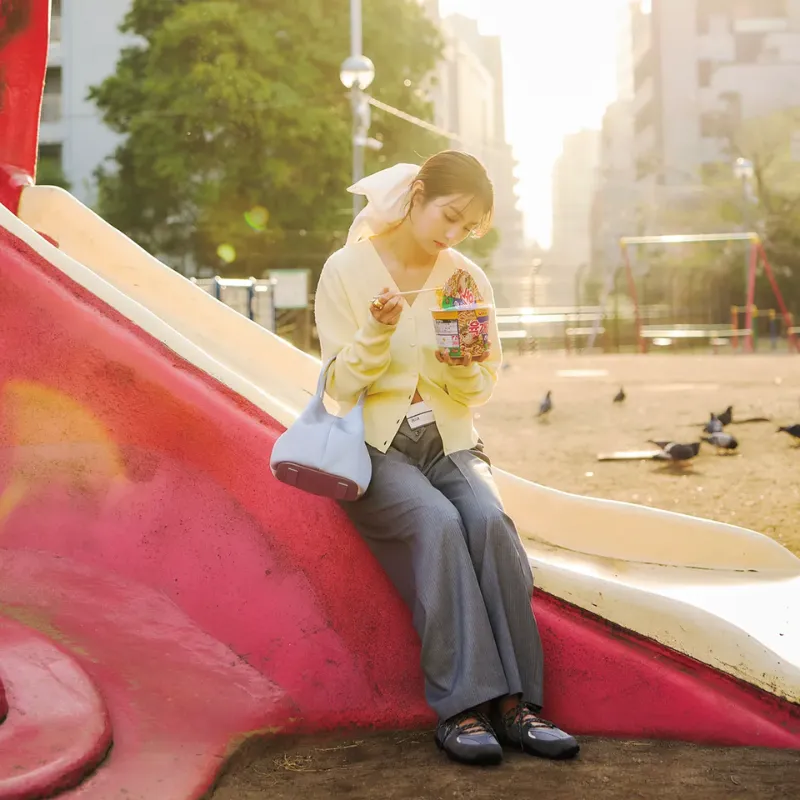 バターイエローのカーディガンをボタンアレンジし、グレーパンツを合わせたスタイル