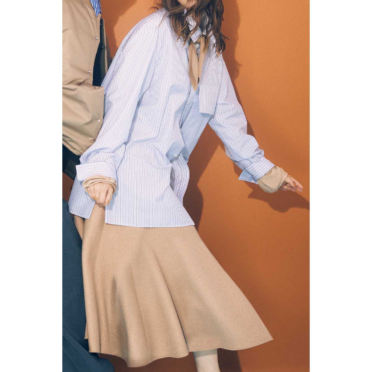 ブルーのストライプシャツにベージュの立体シルエットスカートのコーデ