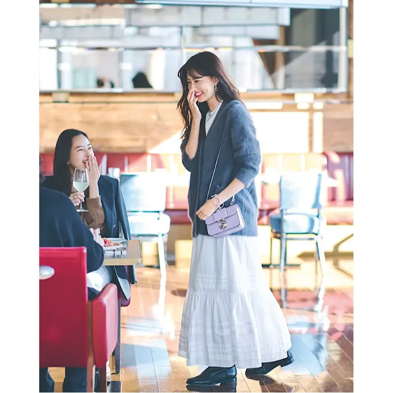 白のコットンスカートにふわふわグレーのカーディガンを合わせ、黒ブーツをプラスした甘辛ミックスコーデ