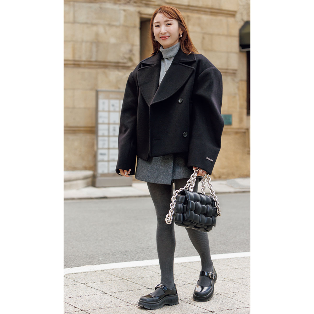 黒のショート丈コートにスコートとグレータイツのコーデ