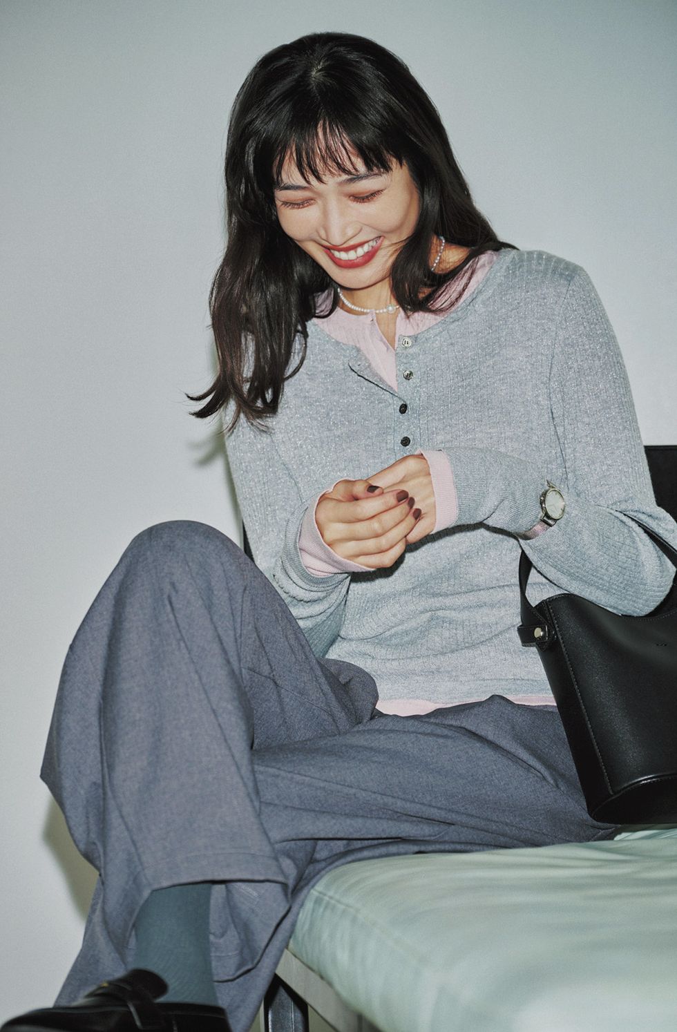 ヘンリーネックの２枚重ねは、生地の分厚さや伸縮性、サイズ感など色々と気にする必要がありますが、２枚をレイヤードしたようなデザインニットを着ていまうという手も。簡単に凝ったオシャレを楽しめます。ニットはStola.、パンツはカデュネ、バッグはヤーキのもの。