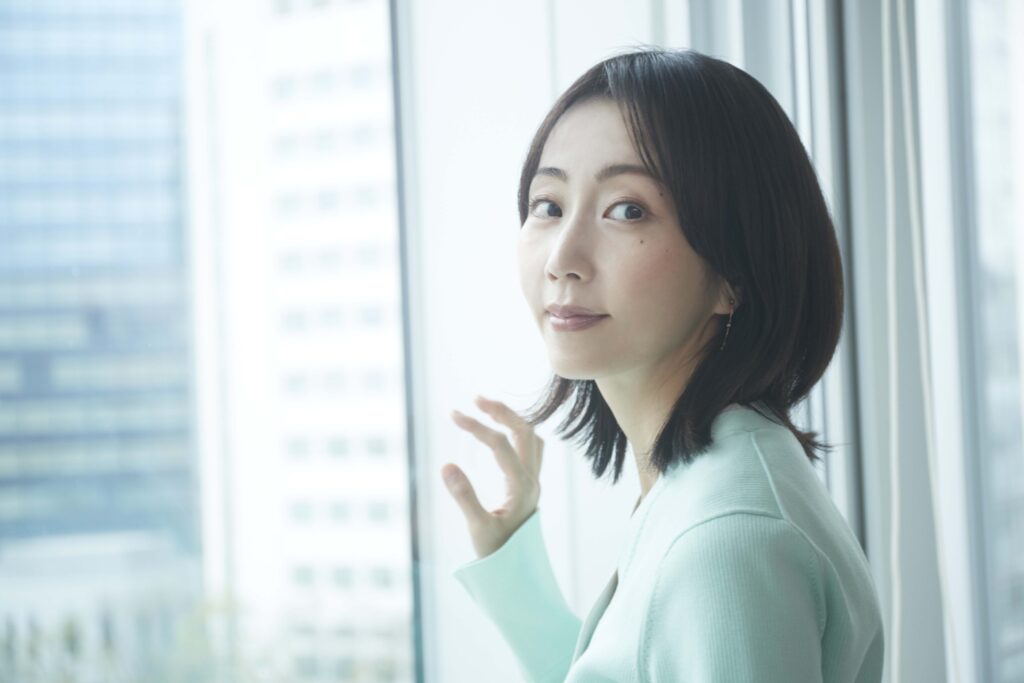 木南晴夏さん　窓に手を当ててカメラに視線を送る画像