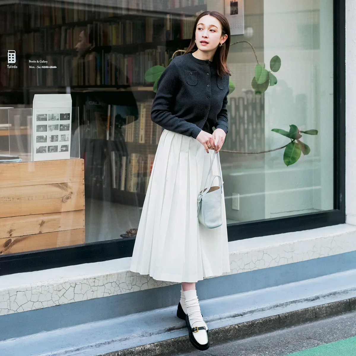 白のプリーツスカート×チャコールグレーのカーディガンの藤井サチさん。